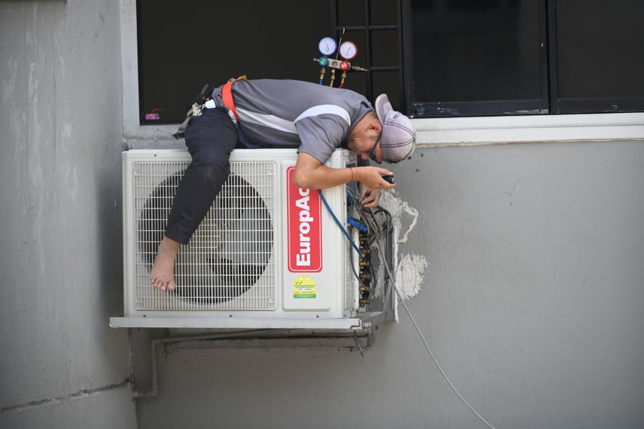 Friendly HVAC technician standing next to a residential unit